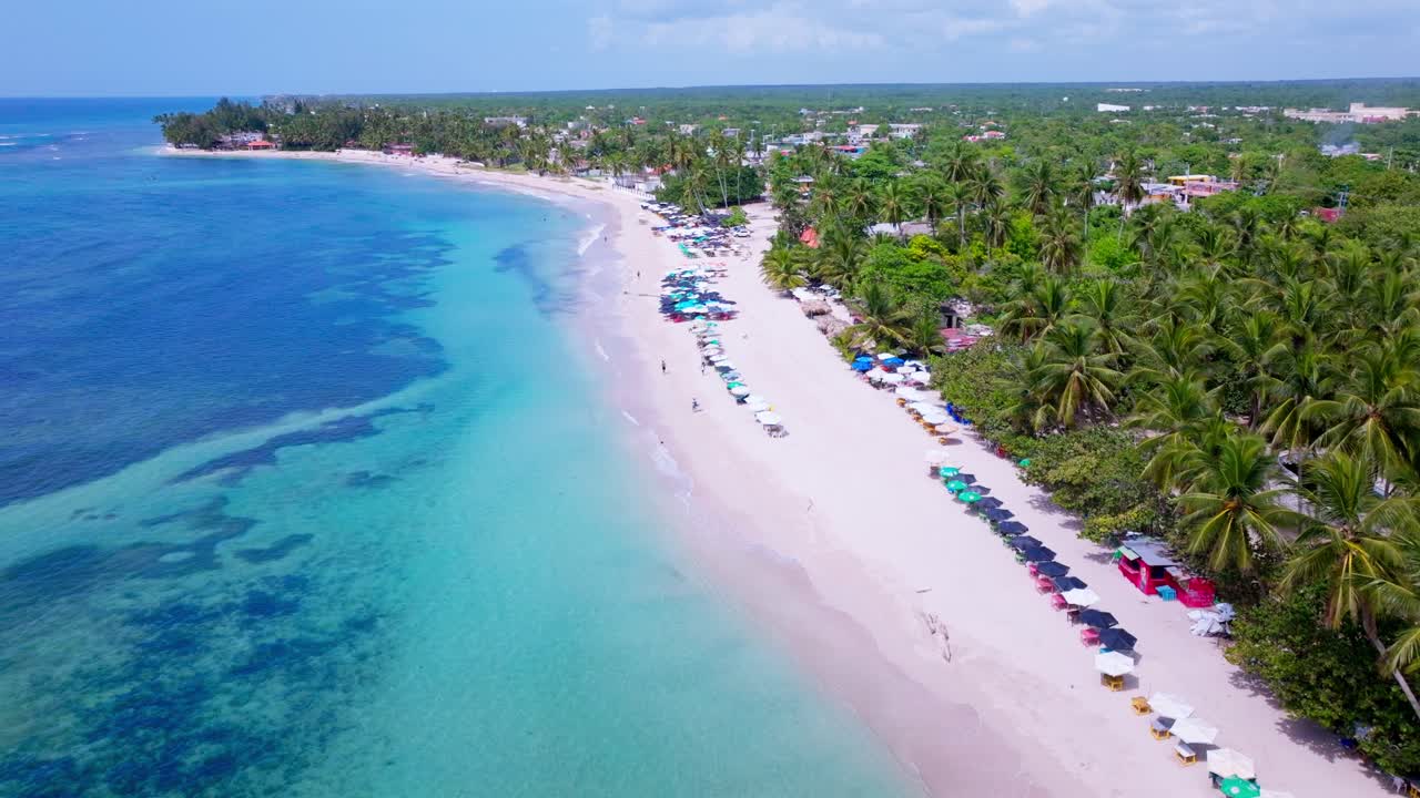 Panoramica aerea di un bellissimo paradiso al sole che mostra oceano cristallino, spiaggia dorata, barche e palme.