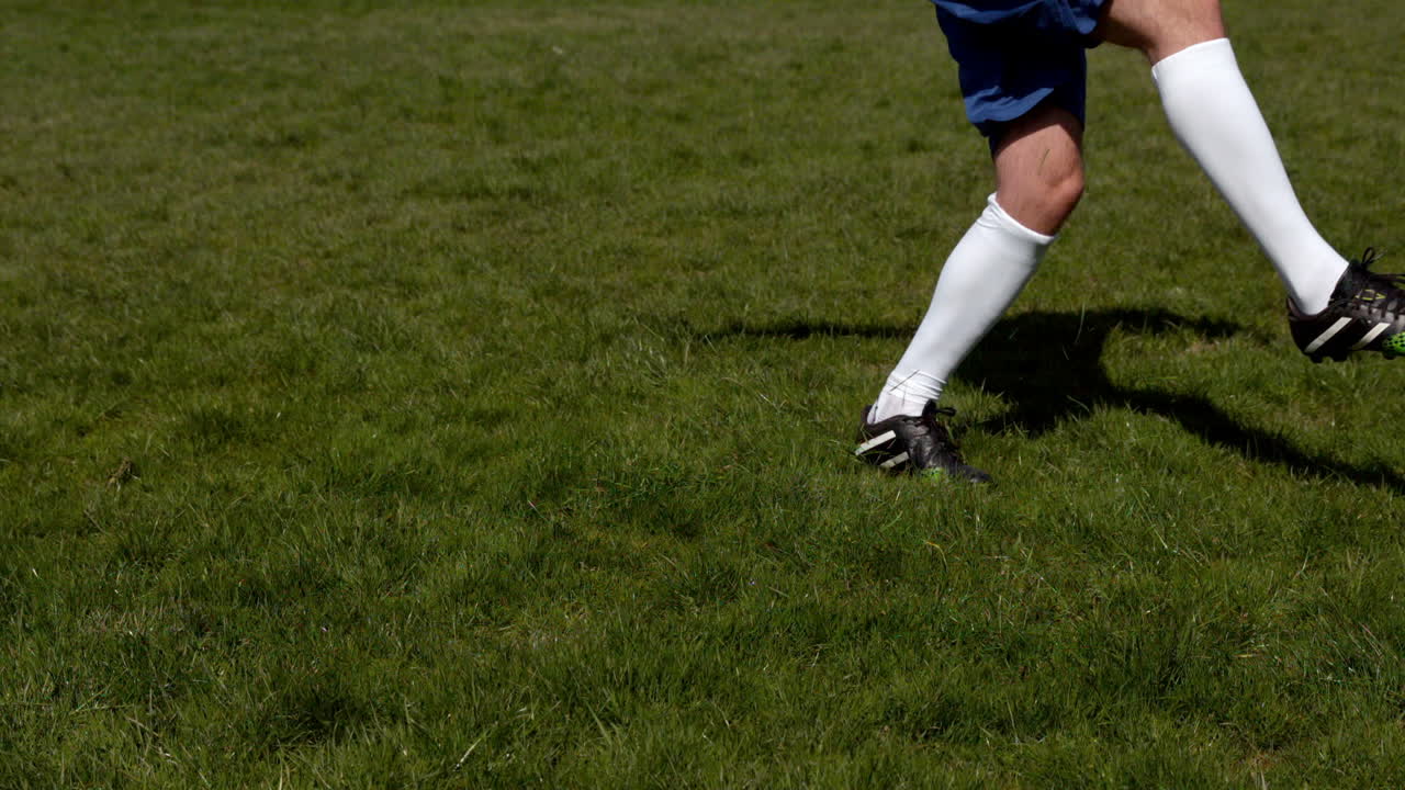 Football player kicking the ball on grass