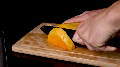 locked off view butternut pumpkin being sliced and diced on wooden chopping board