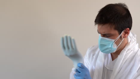 doctor in ppe suit putting glove on latex glove