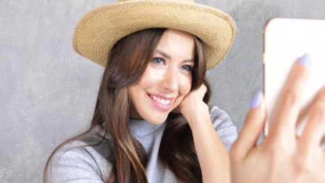 mujer tomando una selfie con un sombrero de paja