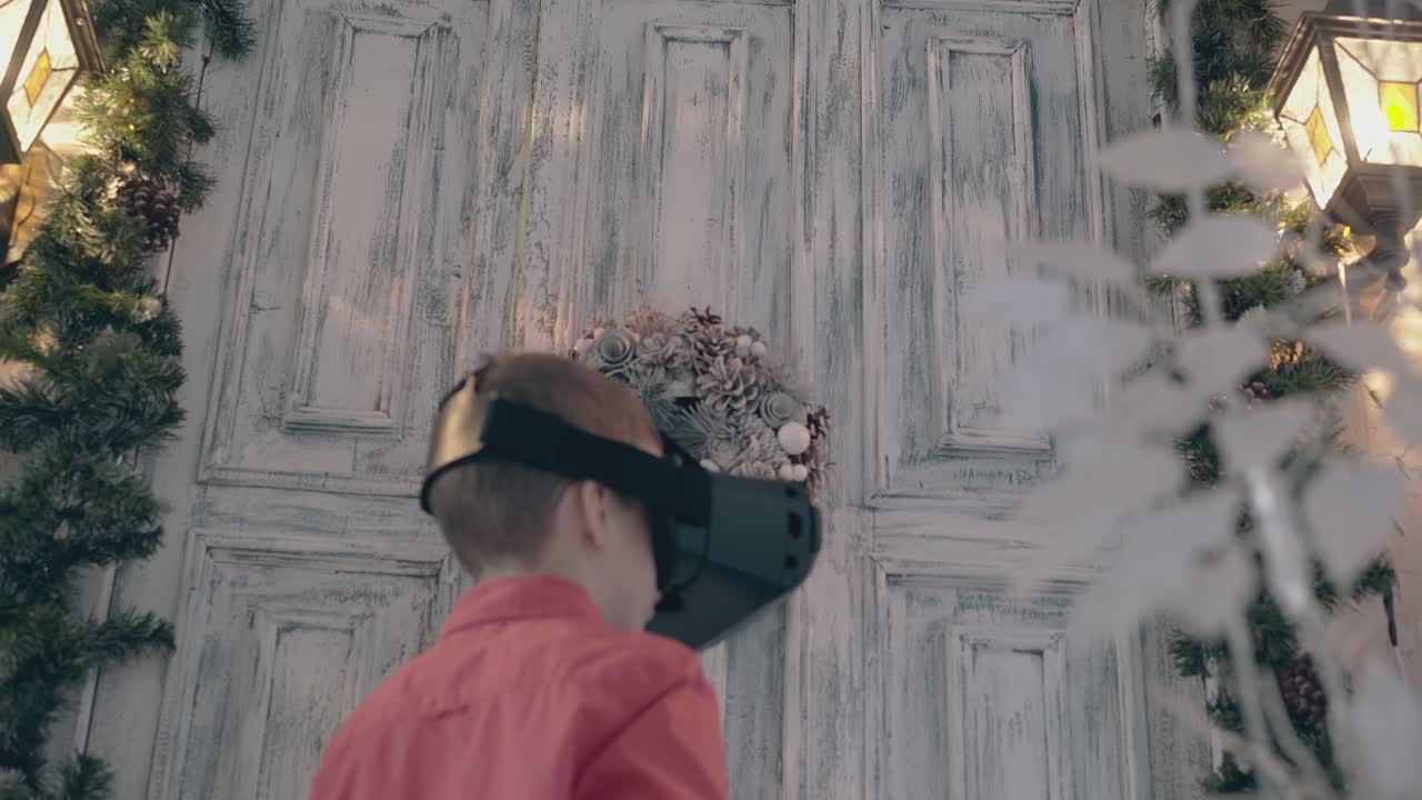 빨간 옷을 입은 어린 남학생이 가상 현실 헤드셋으로 연극을 합니다.