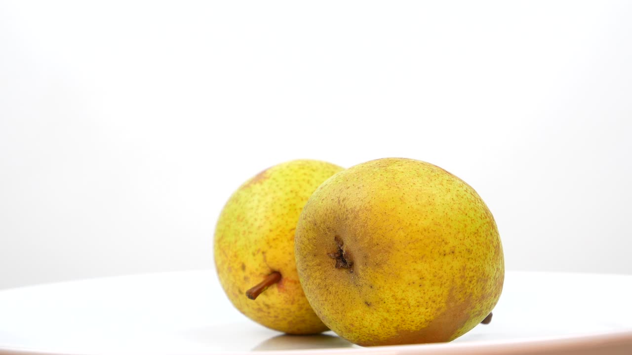 las frutas de la pera giran sobre un fondo blanco. el jugo de la pera. la cosecha de cultivos de jardín. vitrina de la tienda de frutas. frutas frescas. comida dulce. producto vitamínico. lugar para su texto. gira en círculo. video.