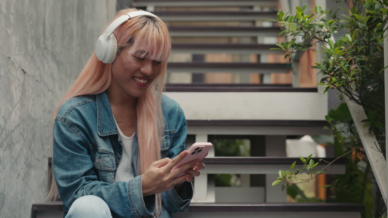 Woman with Pink Hair Sitting on Stairs Using Smartphone