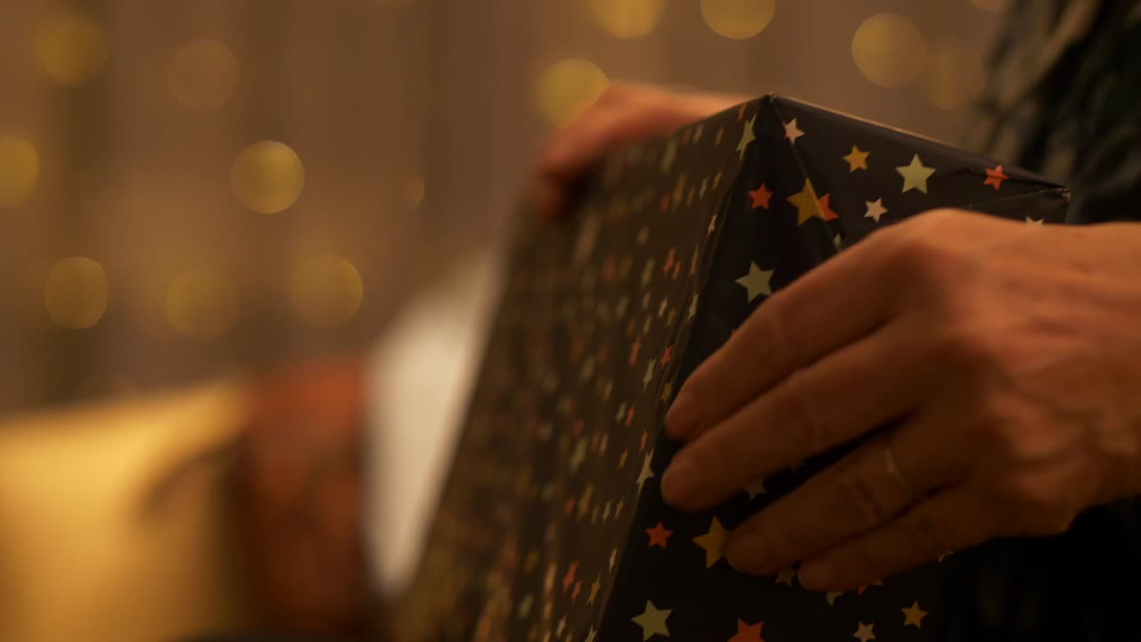 Person opening wrapped Christmas present paper decoration traditional festive celebration