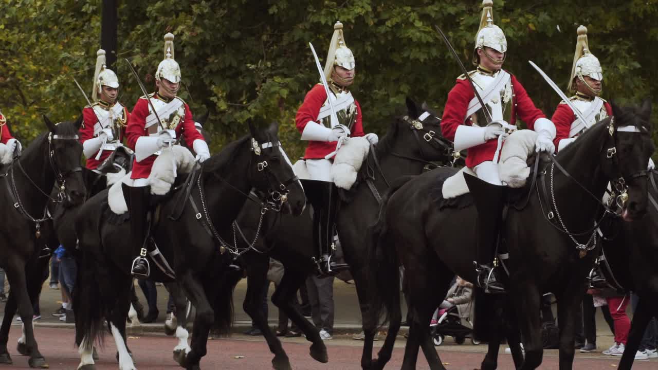 London Queen's Guard silver hatted redcoat horse guards riding black horses and march in procession with spectators watching and taking photos, handheld close up slow motion