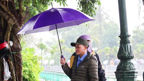 two people share an umbrella during rain