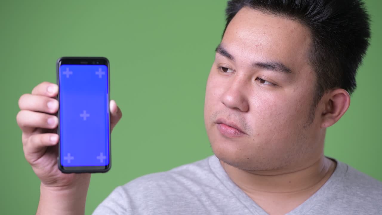 초록색 배경에 젊은 잘생긴 과체중 아시아인