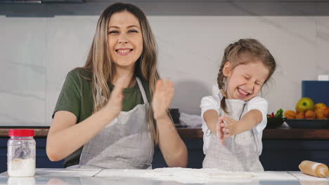 family of little daughter and mother claps hands with flour