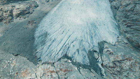 giant waterfall coming from a glacier melting in a lake below due to climate change in the alps, fellaria big waterfalls come down from the glaciers edge, top down view of the mountains and lake below