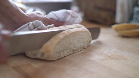 Close-up-of-a-slice-of-white-bread-being-cut-from-a-loaf-on-a-wooden-cutting-board