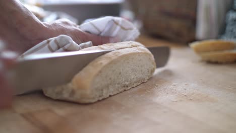 primer plano de una rebanada de pan blanco que se corta de una hogaza en una tabla de cortar de madera