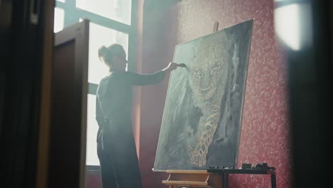 woman painting a leopard portrait in an art studio