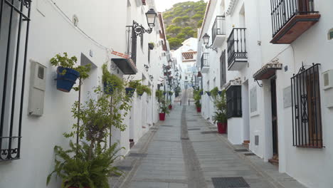 narrow street with white facade houses in spanish town mijas, pan shot