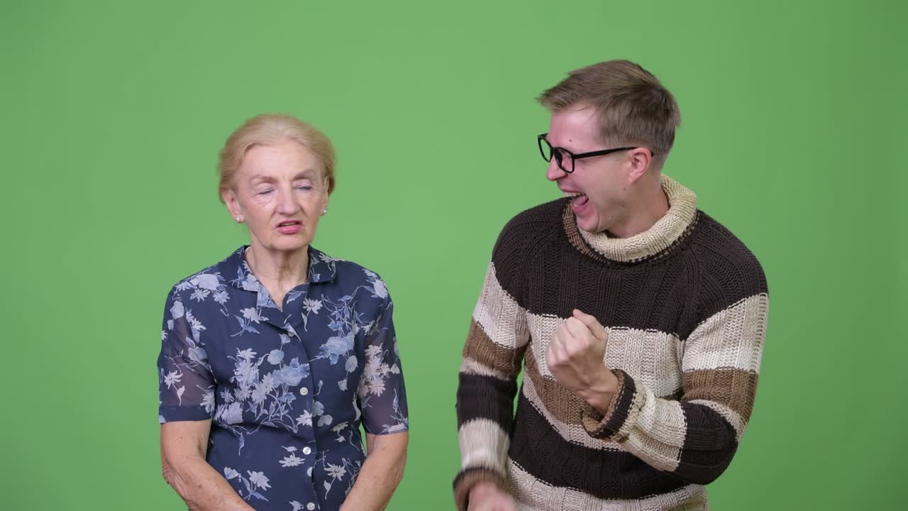 Grandson celebrating while grandmother looking upset against green background