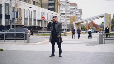 man talking on mobile phone. modern businessman with beard talking on mobile phone in city