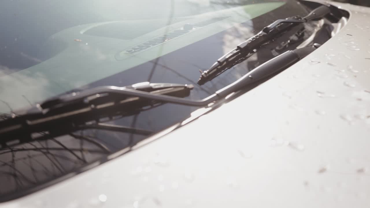 Closer Look At The Wipers On The Windshield And Wet Hood Of A Car On A Bright Sunny Day In Canada - Closeup Shot