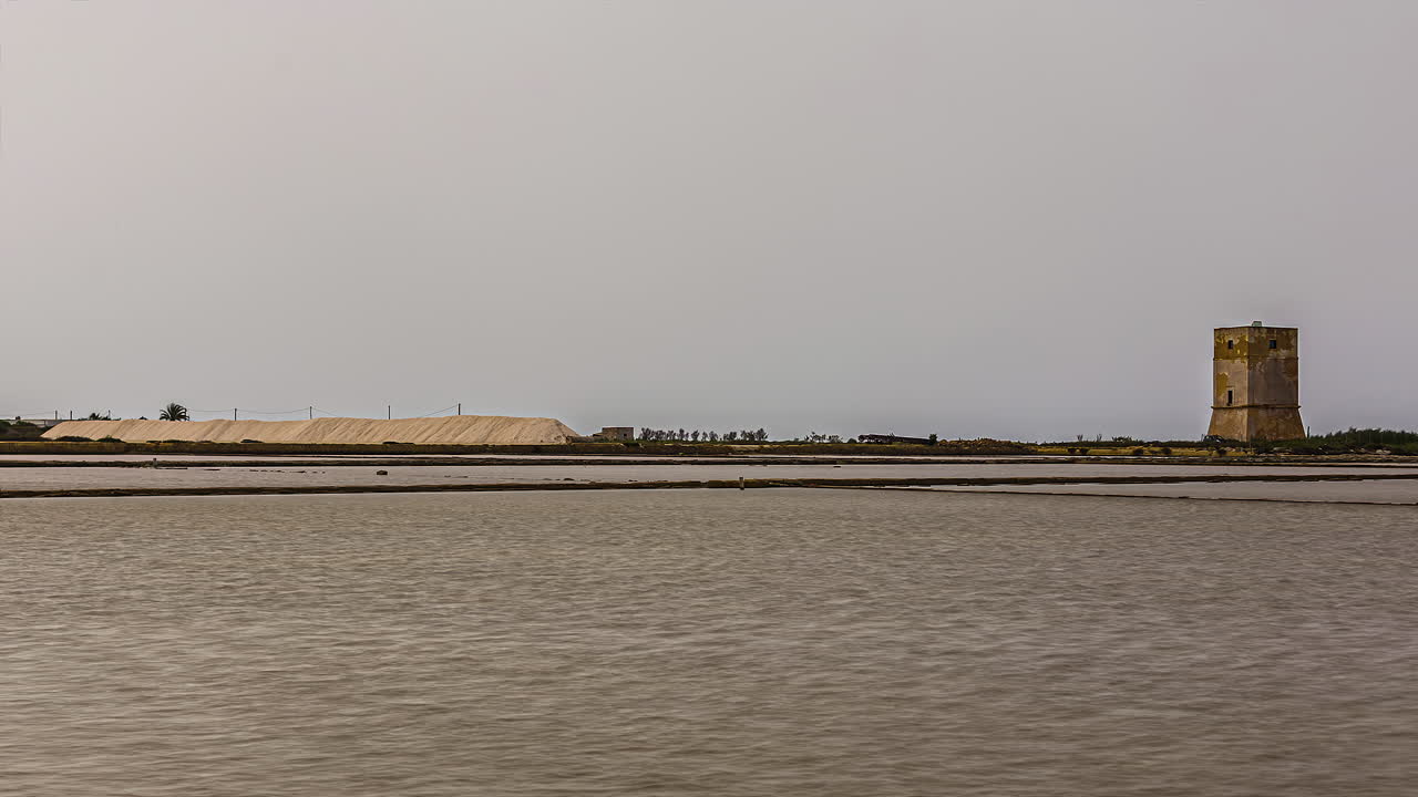 vista lejana de la torre nubia a través de las salinas en trapani, italia