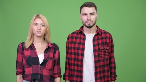 young couple giving thumbs down together