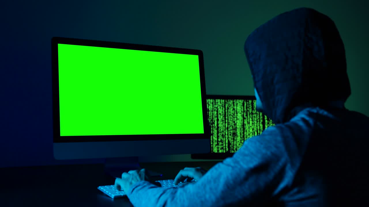 hombre sentado frente a una computadora mirando una pantalla verde.