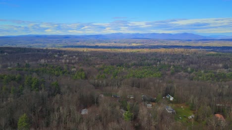 Aerial-side-pan-of-a-vast-valley-with-distant-mountains-on-a-sunny-day-with-blue-skies-in-fall