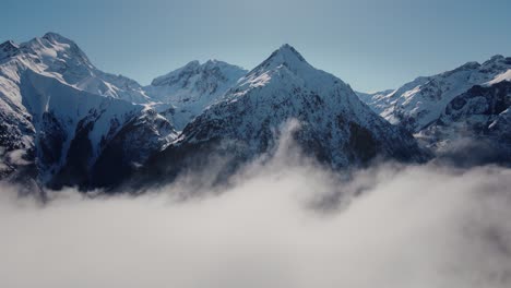 Video-Einer-Drohne,-Die-Durch-Die-Wolken-Auf-Eine-Schneebedeckte-Bergkette-Zufliegt