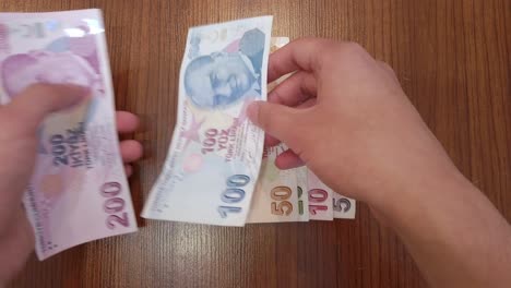 a teenager sorting each banknote of turkish lira by value, with portrait of mustafa kemal atatürk, founder of republic of türkiye on top