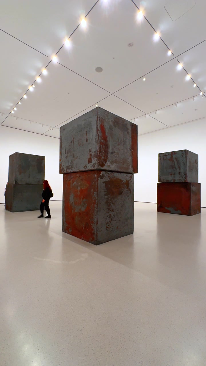 New York, USA, 12 August 2025: Monumental steel sculptures in modern hall. Visitors walk among massive weathered steel blocks in a contemporary exhibit.