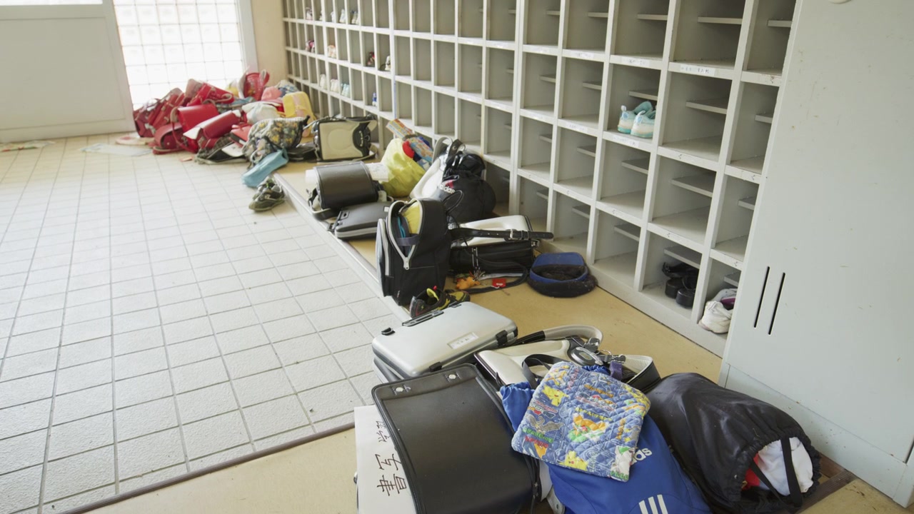 Backpacks and shoes lie abandoned in an evacuated Fukushima school entrance.