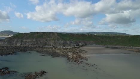 Aerial-pan-view-of-North-bay,-Scarborough,-North-Yorkshire-with-cliffs,-coastline,-ocean,-and-castle