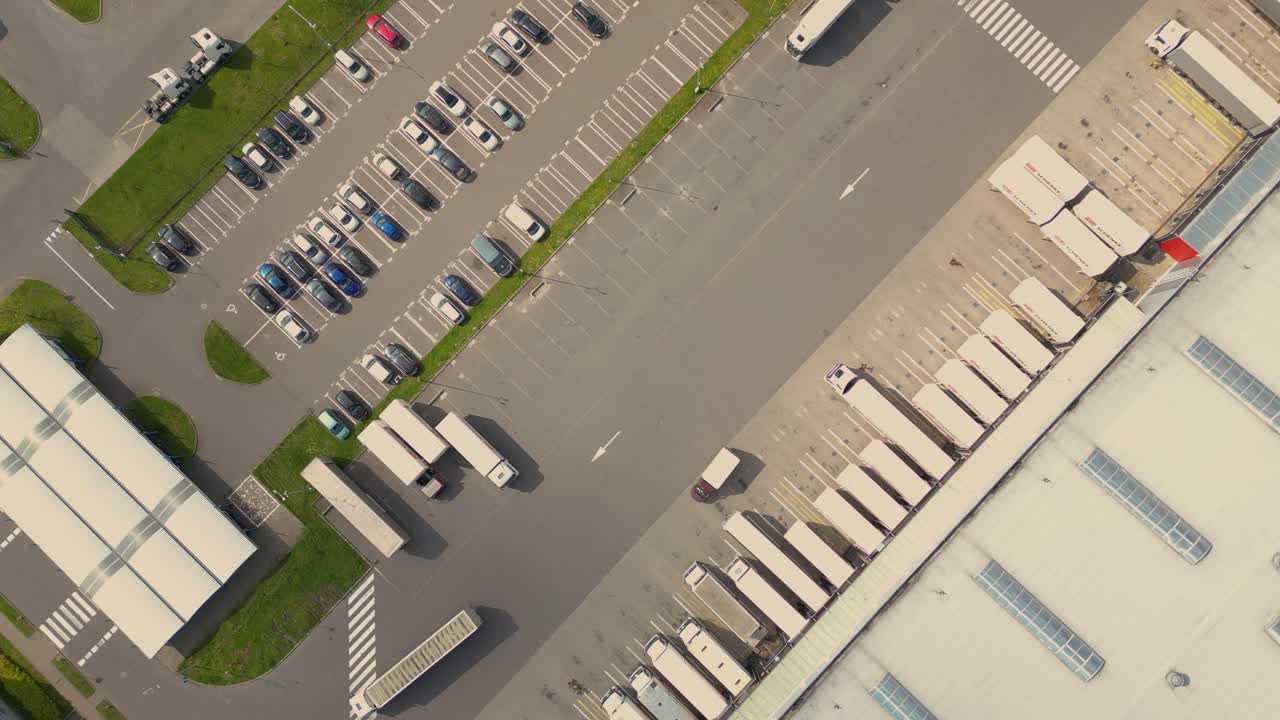 Droneoversigt over en gruppe store moderne industrilagre eller fabriksbygninger i et forstadsområde.