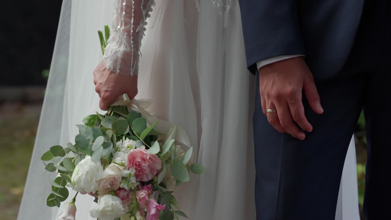 Close-up of bride and groom standing together, with the bride holding a floral bouquet and both wearing wedding attire, capturing a romantic and elegant wedding moment