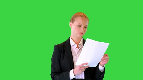 joven mujer de negocios mirando a través de documentos mientras camina en una pantalla verde, clave de croma