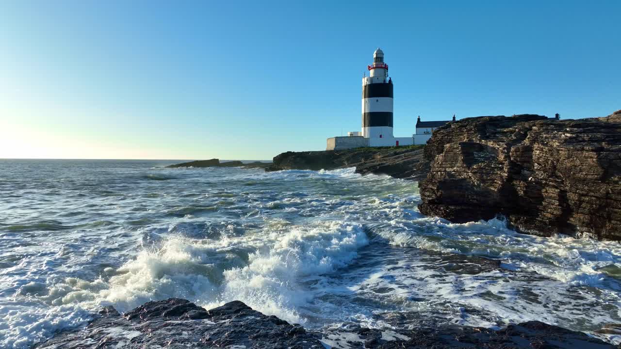 Faro di Hook Head, Wexford, Irlanda: mare agitato e onde che sferzano le rocce dopo una tempesta atlantica in primavera