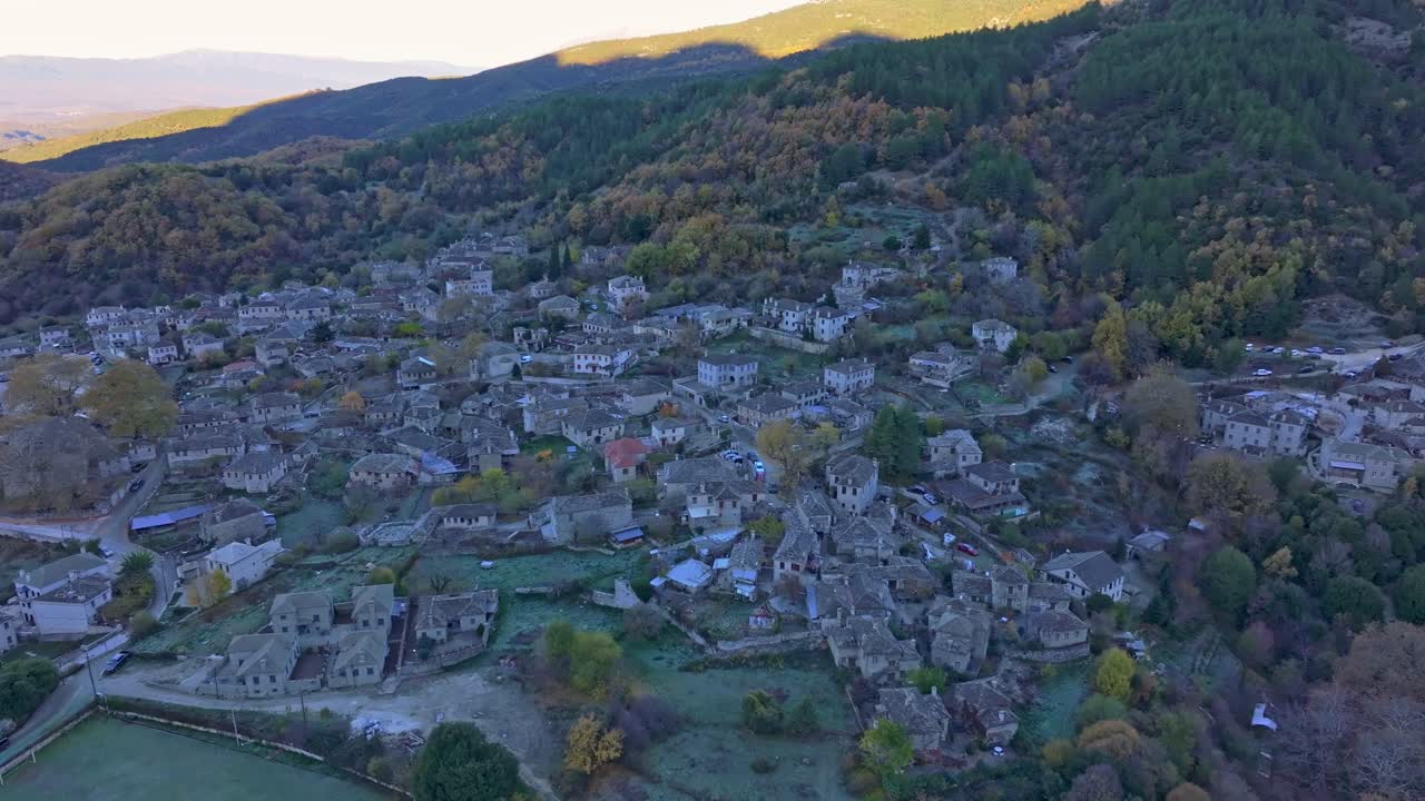 Ripresa aerea dell'alba su una foresta autunnale e un villaggio, Grecia