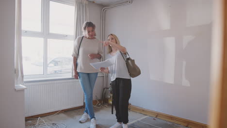 two female friends buying house for first time looking at house survey in room to be renovated