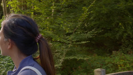 woman wearing sports clothing carrying yoga mat standing on bridge in forest looking around enjoying peace and beauty of nature 4