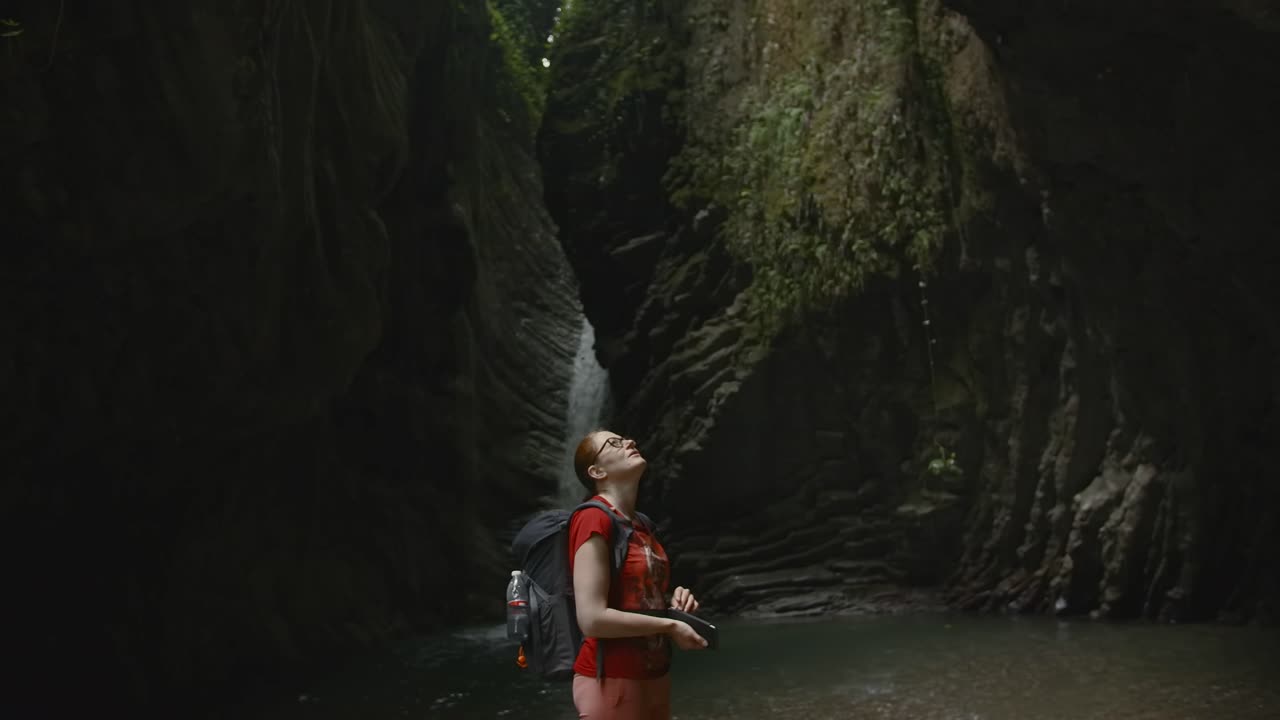 Woman Hiking in a Canyon with Waterfall