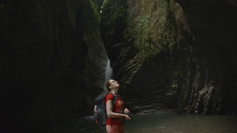 mujer caminando en un cañón rocoso con cascada