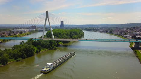 Aerial shot of Neuwied, Germany, capturing a cargo vessel making its path under the modern Rhine bridge.