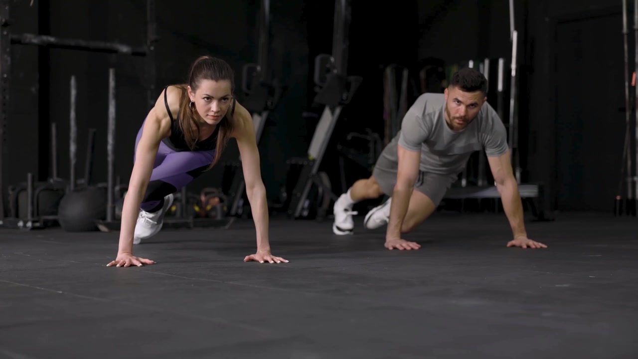 Hombre y mujer realizando el ejercicio de escaladores en un gimnasio moderno