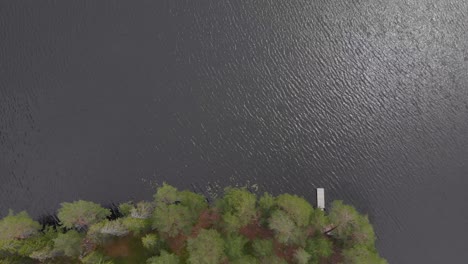 aerial footage of a bridge in the forest at the edge of the lake at skoludden looking straight down at the viewpoint from where you see the island that floats up every summer