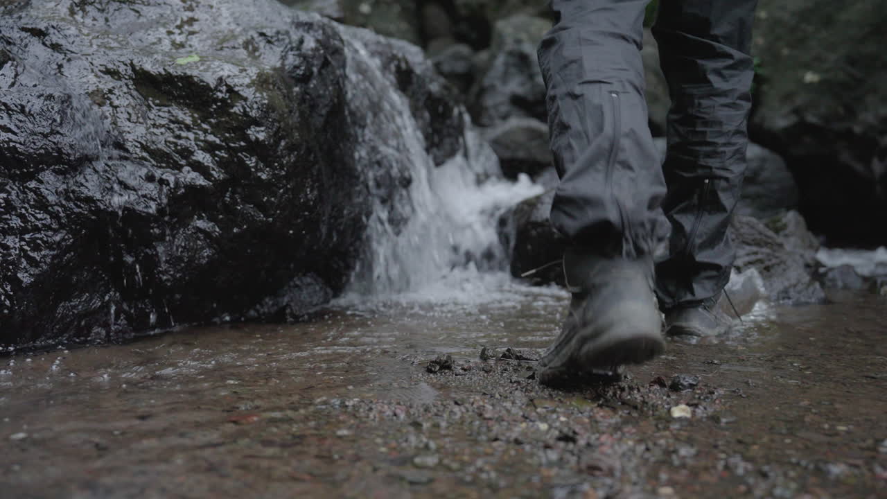 bajo de corriente en la naturaleza, pies que pasan por el agua y escalar en la roca