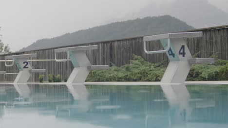 outdoor swimming pool springboard in rain with raindrops in slow motion