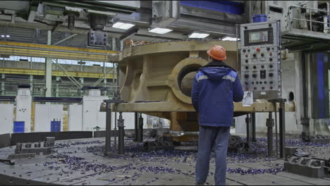 worker observing metal part on lathe machine in industrial setting