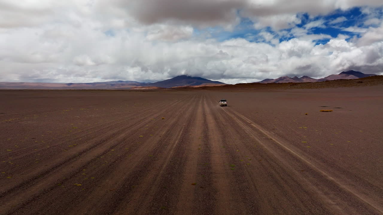 Drone follow car on plain and vast remote Siloli Desert in Bolivia. Road trip adventure, travelling