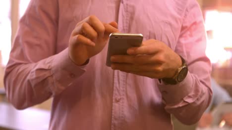 hombre de negocios enviando un mensaje de texto desde su teléfono