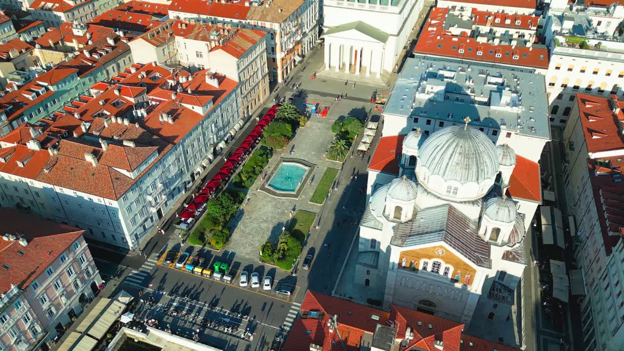 Drone footage of Piazza Sant’Antonio Taumaturgo and Canal Grande in Trieste, with the iconic church, red-tiled rooftops, and Mediterranean charm in stunning aerial detail.