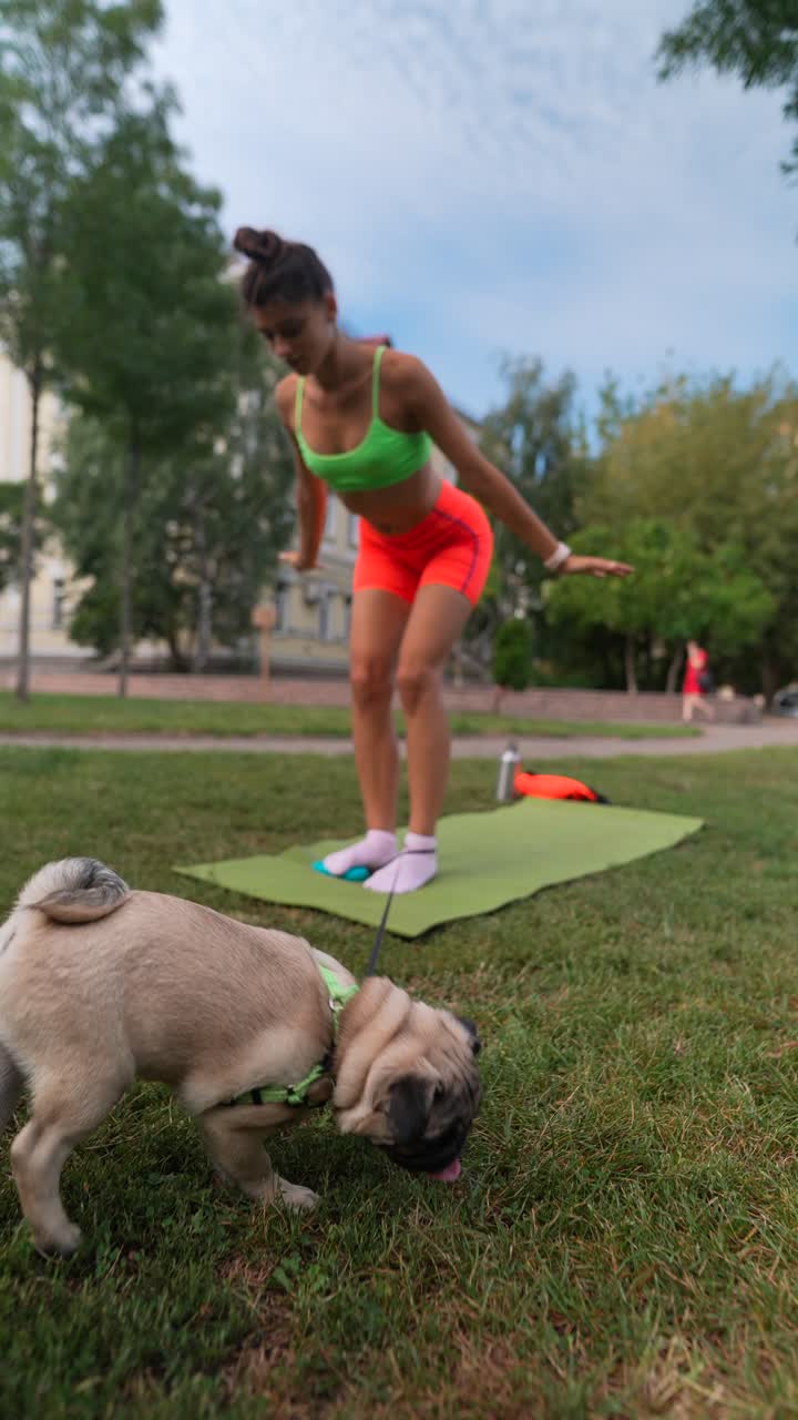 mujer practicando yoga en un parque con un pug