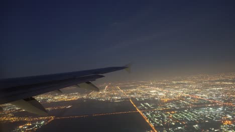 plane flying over glowing city at night on take off